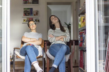 Zwei Freundinnen sitzen zu Hause in der Küche mit offener Tür und genießen die Sonne - MOEF01953