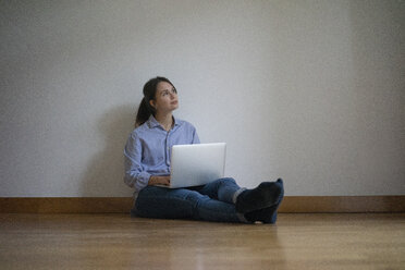 Young woman sitting on floor, using laptop - MOEF01967