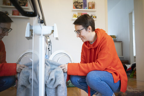 Junge Frau wäscht zu Hause die Wäsche, lizenzfreies Stockfoto