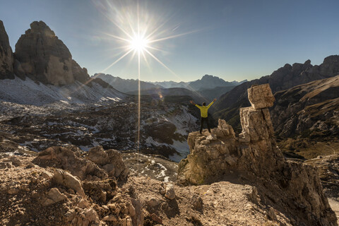 Italy, Tre Cime di Lavaredo, man hiking and looking at the valley with peaks and sun over the horizon stock photo