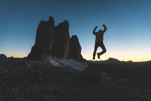 Italien, Drei Zinnen, Silhouette eines Mannes beim Sprung auf die drei Gipfel in der Abenddämmerung - WPEF01339