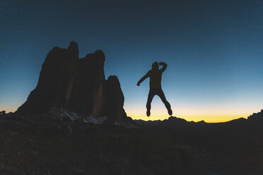 Italy, Tre Cime di Lavaredo, silhouette of a man jumping at the three peaks at dusk - WPEF01340
