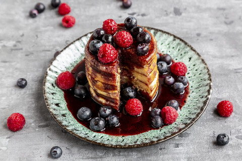 Pfannkuchen mit Heidelbeeren, Himbeeren und schwarzem Johannisbeersirup, lizenzfreies Stockfoto