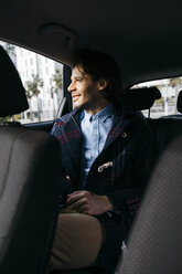Lächelnder Mann sitzt auf dem Rücksitz eines Autos und schaut aus dem Fenster - JRFF02525