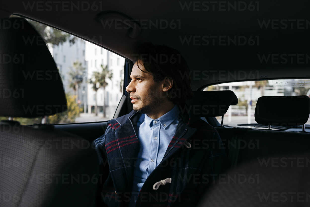 Mann sitzt auf dem Rücksitz eines Autos und schaut aus dem Fenster,  lizenzfreies Stockfoto
