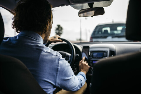 Geschäftsmann fährt Auto und benutzt ein Handy als Navigationssystem, lizenzfreies Stockfoto