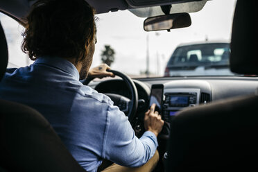 Geschäftsmann fährt Auto und benutzt ein Handy als Navigationssystem - JRFF02541