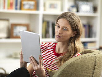 Junge Frau entspannt sich zu Hause und benutzt ein Tablet - ABRF00281