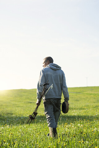 Landwirt, der auf seinem Land durch eine Wiese mit Löwenzahn spaziert, lizenzfreies Stockfoto