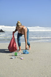 Pregnant woman cleaning the beach from plastic waste - ECPF00359