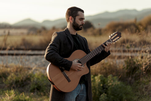 Male musician with beard playing the guitar in the countryside - LOTF00057