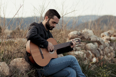 Männlicher Musiker mit Bart spielt Gitarre auf dem Lande - LOTF00059