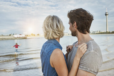 Germany, Duesseldorf, affectionate young couple with daughter at Rhine riverbank - RORF01665