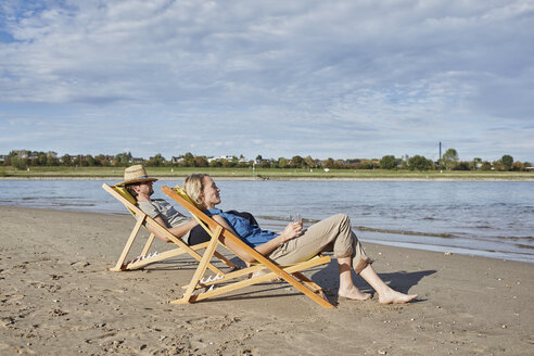 Junges Paar in Liegestühlen entspannt am Flussufer - RORF01708