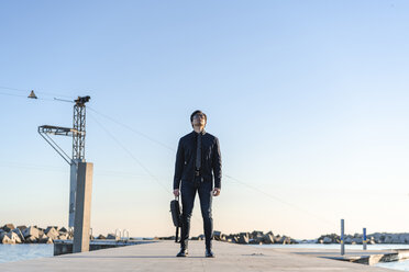 Fashionable young businessman with backpack standing on jetty - AFVF02318