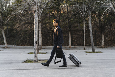 Young businessman with rolling suitcase and backpack - AFVF02330