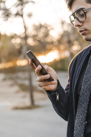 Junger Geschäftsmann schaut auf sein Handy, lizenzfreies Stockfoto