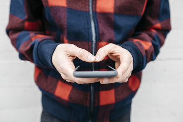 Hands of young man with chequered jacket using phone - JRFF02561