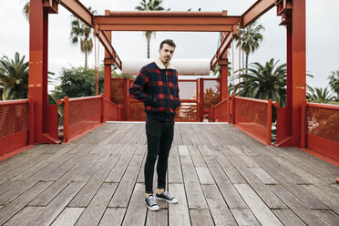 Young man with casual clothes on a red bridge looking at camera - JRFF02570