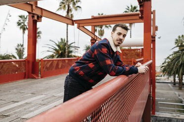 Young man with casual clothes on a red bridge looking at camera - JRFF02571