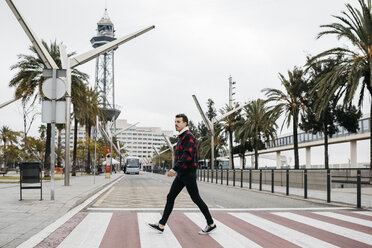 Junger Mann in Freizeitkleidung auf einem Fußgängerüberweg in Barcelona - JRFF02573