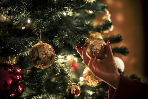 Weibliche Hand hält goldene Weihnachtskugel, Nahaufnahme, lizenzfreies Stockfoto