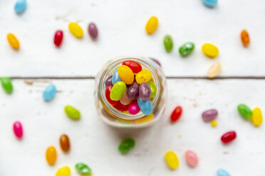 Glass of colourful sweet jellybeans on white wood - SARF04078