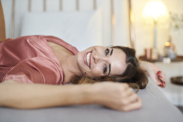 Porträt einer glücklichen jungen Frau im Morgenmantel im Bett liegend - PNEF01273