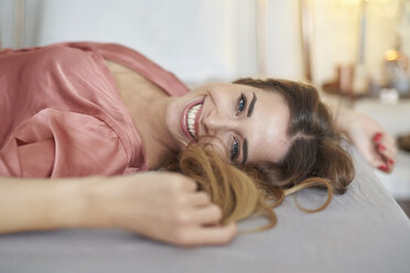 Porträt einer glücklichen jungen Frau im Morgenmantel im Bett liegend - PNEF01274