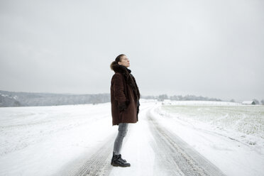 Ältere Frau steht auf einem Feldweg im Winter - FLLF00059