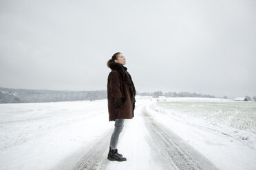 Mature woman standing on field way in winter - FLLF00059