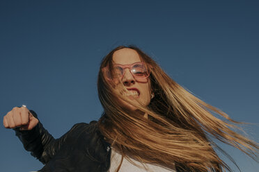 Porträt einer aggressiven jungen Frau, die unter blauem Himmel schlägt - DMGF00005