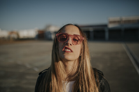 Portrait of young woman with defiant attitude wearing sunglasses outdoors stock photo