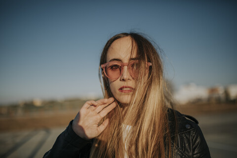 Porträt einer langhaarigen jungen Frau mit Sonnenbrille im Freien, lizenzfreies Stockfoto