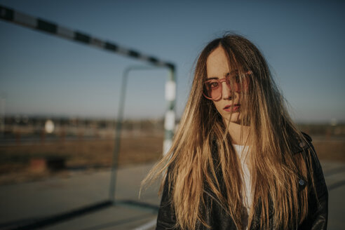 Porträt einer jungen Frau mit Sonnenbrille auf einem Sportplatz - DMGF00009