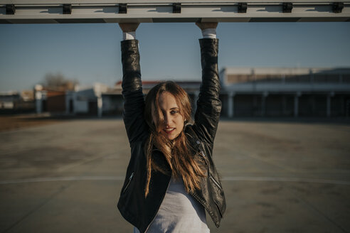 Porträt einer jungen Frau, die an einem Tor auf einem Sportplatz hängt - DMGF00010