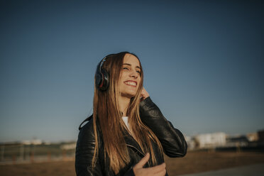 Happy young woman listening music with headphones outdoors - DMGF00013