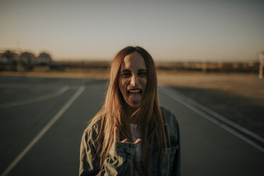 Portrait of young woman outdoors sticking out tongue - DMGF00027