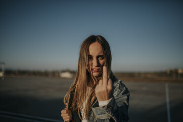 Portrait of young woman outdoors giving the finger - DMGF00028