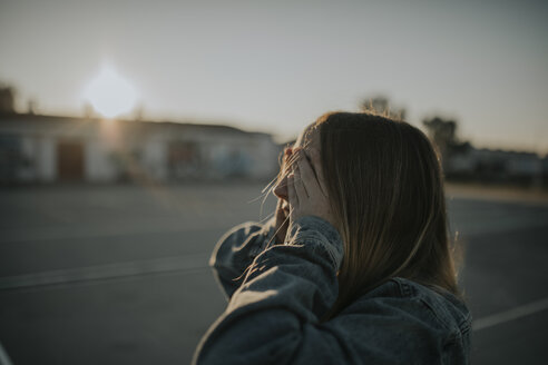 Junge Frau bedeckt ihre Augen bei Sonnenuntergang - DMGF00034