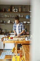 Young man preparing food at home, slicing bread - PESF01106