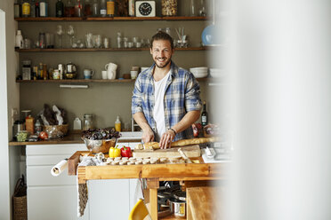 Young man preparing food at home, slicing bread - PESF01107