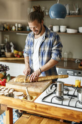 Young man preparing food at home, slicing bread - PESF01110