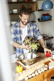 Junger Mann bei der Essenszubereitung zu Hause, Reinigung von Salat - PESF01113