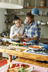 Young couple preparing spaghetti together, using online recipe - PESF01120