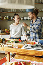 Young couple preparing food together, tasting spaghetti - PESF01122