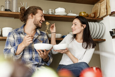 Glückliches Paar sitzt in der Küche und isst Spaghetti - PESF01128