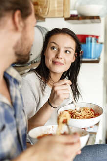 Glückliches Paar sitzt in der Küche und isst Spaghetti - PESF01129