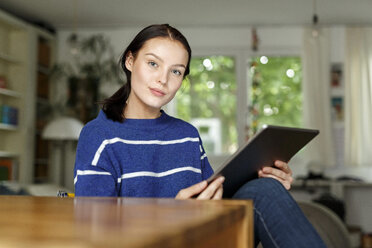 Junge Frau sitzt zu Hause und benutzt ein digitales Tablet - PESF01135