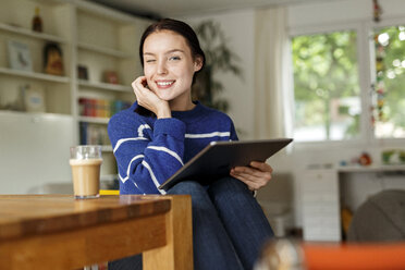 Junge Frau sitzt zu Hause und benutzt ein digitales Tablet - PESF01139